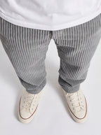 Gray striped pants and white sneakers on a light gray background