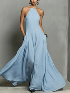 Woman wearing a long light blue dress against a gray background