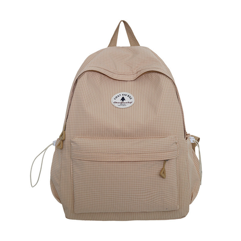 A beige gingham backpack with a front zippered pocket and a circular white brand patch, shown against a plain white background.