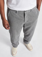Person wearing gray striped pants and white sneakers on a light background